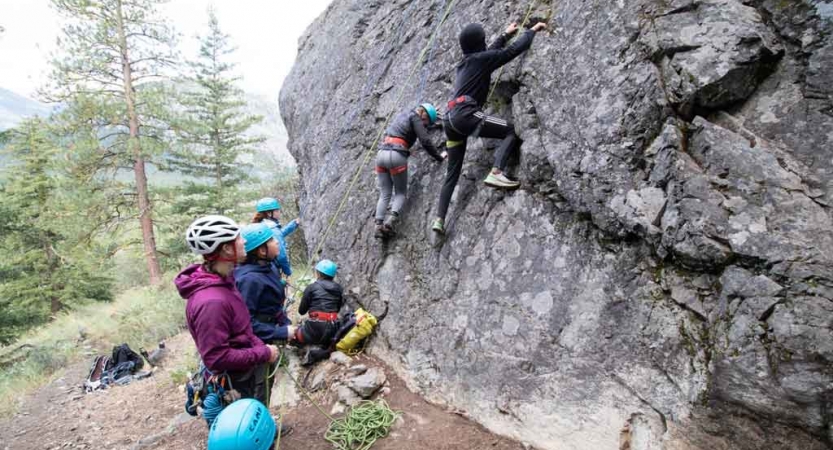 two students ascend over a rocky landscape with a mountain in the background